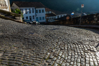 Cobblestone street by buildings in city at night