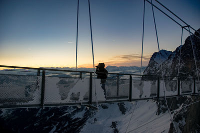 Man on horse by sea against sky during sunset
