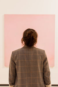 Rear view of woman standing against wall