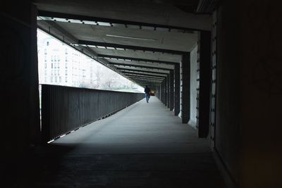 Rear view of man walking in corridor of building