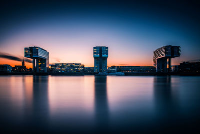 River by illuminated buildings against sky at night