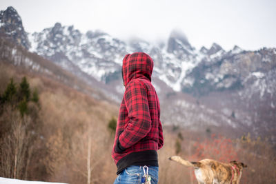 Rear view of person with dog on snow