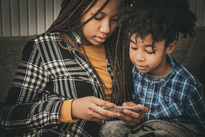 Siblings using smart phone at home