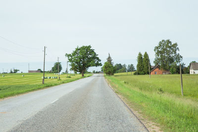 Road amidst field against clear sky