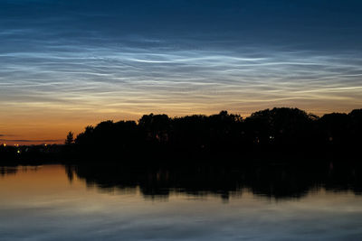 Silhouette trees by lake against sky during sunset