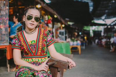 Portrait of woman wearing sunglasses sitting in market