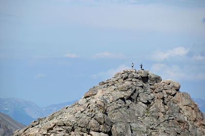 Low angle view of man standing on rock against sky