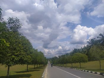 Road by trees against sky