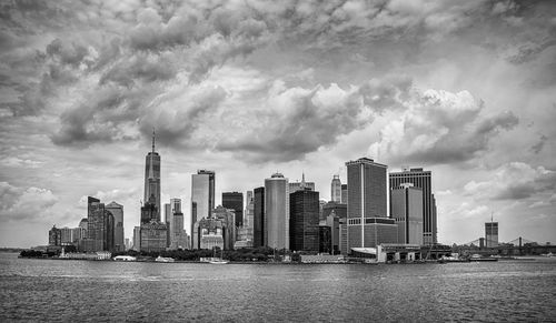 Modern buildings by river against sky in city