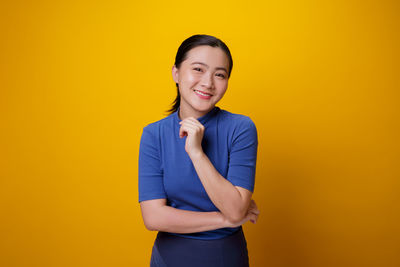 Portrait of a smiling young woman against yellow background