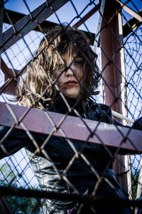 Low angle portrait of woman trapped in metallic cage
