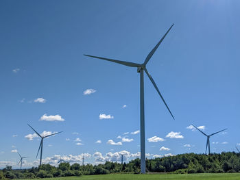 Wind turbines on field against sky