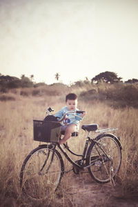 Portrait of baby boy sitting on bicycle on grassy field