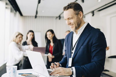 Smiling businessman working over laptop while standing in office seminar