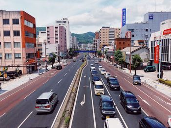 Vehicles on road amidst buildings in city against sky