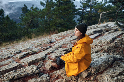 Rear view of man sitting on rock