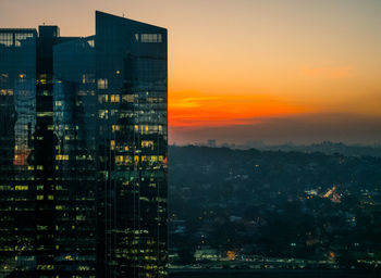 Illuminated buildings against sky during sunset