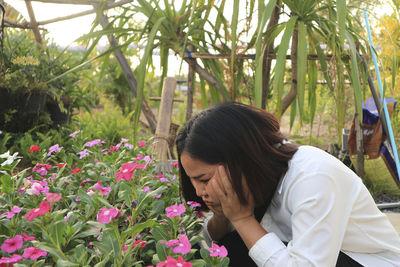 Rear view of woman with flowers against plants