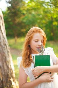 Cute girl holding book and flowers