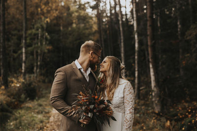 Young couple standing by tree in forest