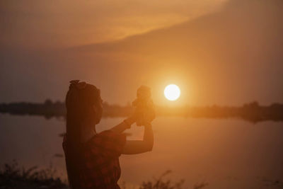 Side view of silhouette woman standing against sky during sunset