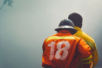 Rear view of firefighters standing against smoke