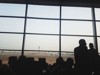 Silhouette people sitting at airport against sky