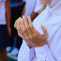 Midsection of schoolgirl standing in prayer position