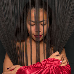 Portrait of woman lying down on floor against black background