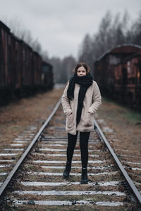 Full length portrait of teenage girl standing on railroad track