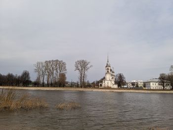 Scenic view of river by buildings against sky