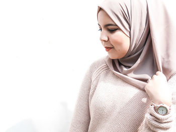 Close-up of smiling young woman against white background