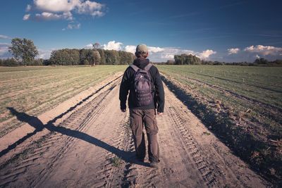 Traveler with backpack walking the dirt road, view in sunny day