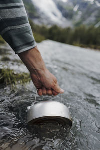 Cropped hand filling water in container at river