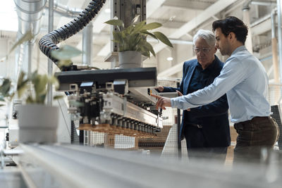 Young man discussing with colleague over machinery in industry