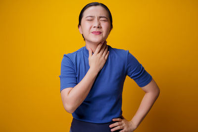 Portrait of smiling girl standing against yellow background