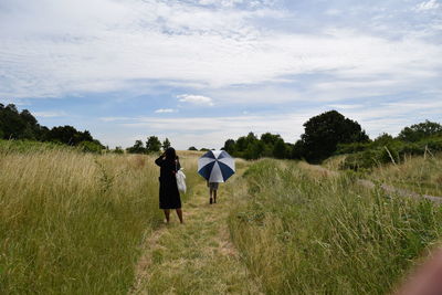 Rear view full length of woman standing on grassy field against sky