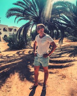 Full length of young man standing on palm tree