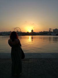 Woman watching sunset and modern city by bay