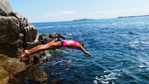 Woman diving into sea against sky