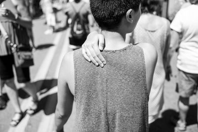 Rear view of woman with short hair standing on footpath during sunny day