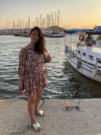 A young woman is in marina in bodrum surrounded by yachts with sunset on a background