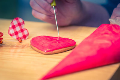 Cropped hand making cookies on table