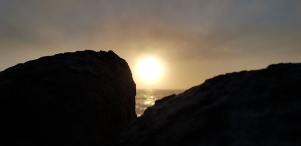 Silhouette rock formation against sky during sunset