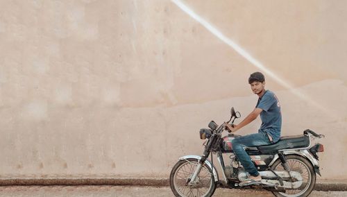 Side view of man riding bicycle against wall