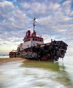 Abandoned ship on beach against sky