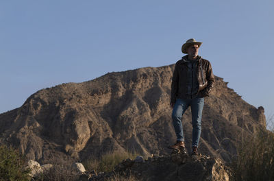 Adult man in cowboy hat standing on rock in desert, almeria, spain