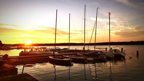 Boats moored at harbor during sunset