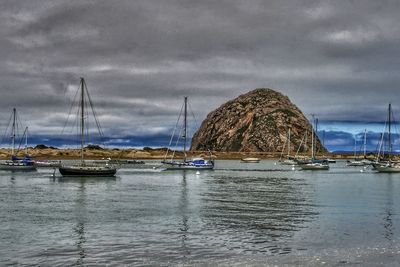 Sailboats moored on sea against sky