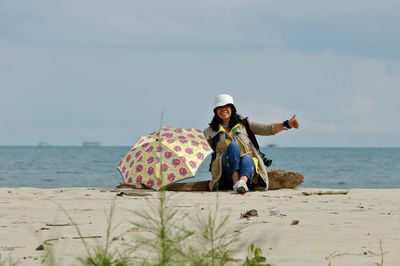 Man sitting on beach against sky